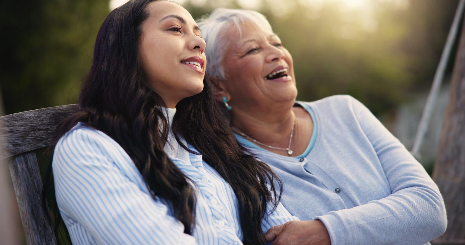 Two women laughing together outdoors, one younger and one older